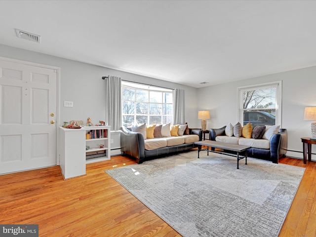 living room with visible vents, baseboard heating, and wood finished floors