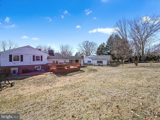 exterior space with brick siding, a yard, a chimney, fence, and a wooden deck