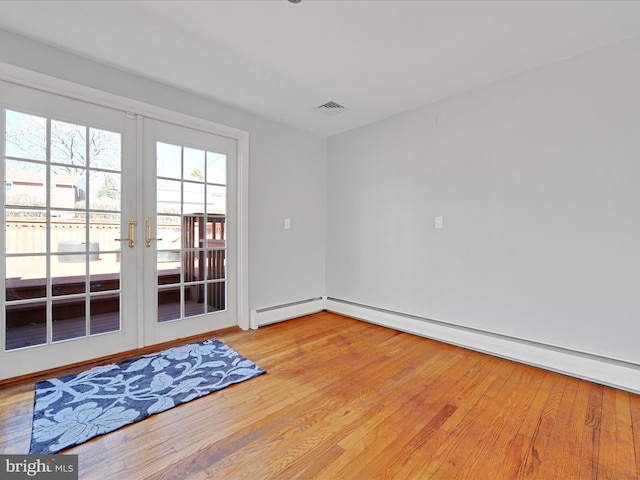 unfurnished room with a baseboard heating unit, french doors, light wood-type flooring, and visible vents