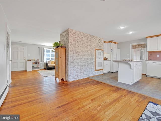 kitchen featuring open floor plan, white appliances, white cabinetry, and light wood-style floors