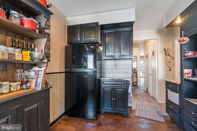 kitchen featuring dark wood-style floors, freestanding refrigerator, light countertops, and open shelves