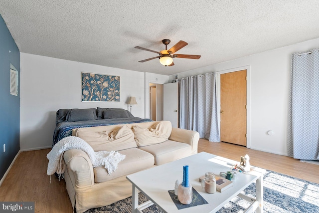 bedroom with a textured ceiling, wood finished floors, and a ceiling fan