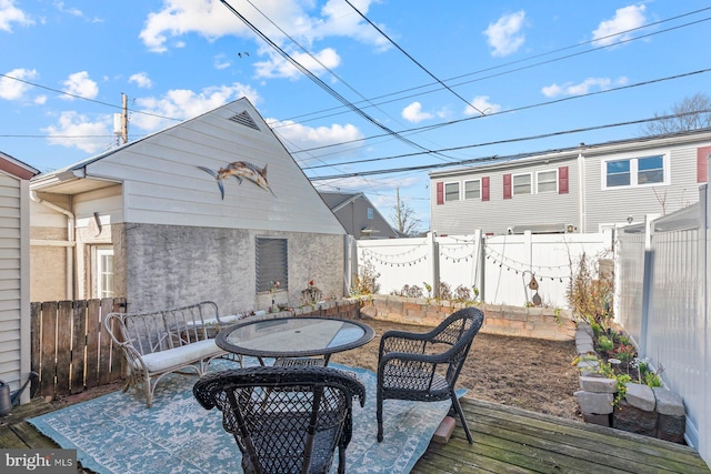 wooden deck with outdoor dining space and a fenced backyard