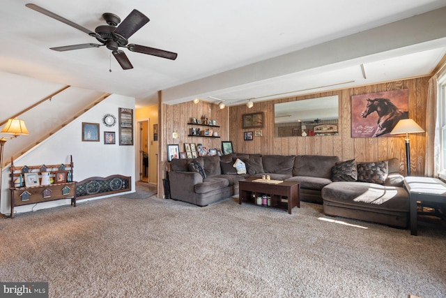 living area featuring wood walls, carpet flooring, and a ceiling fan