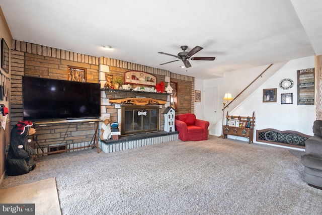 living room with carpet floors, a glass covered fireplace, stairway, and a ceiling fan