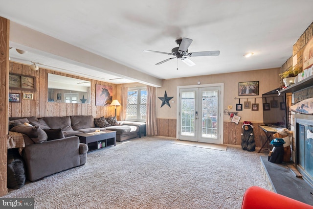 living room featuring wainscoting, ceiling fan, french doors, carpet floors, and wood walls