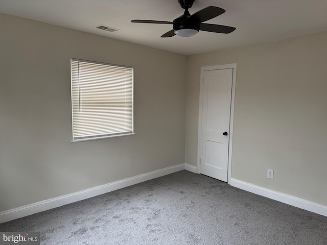 carpeted spare room with ceiling fan, visible vents, and baseboards