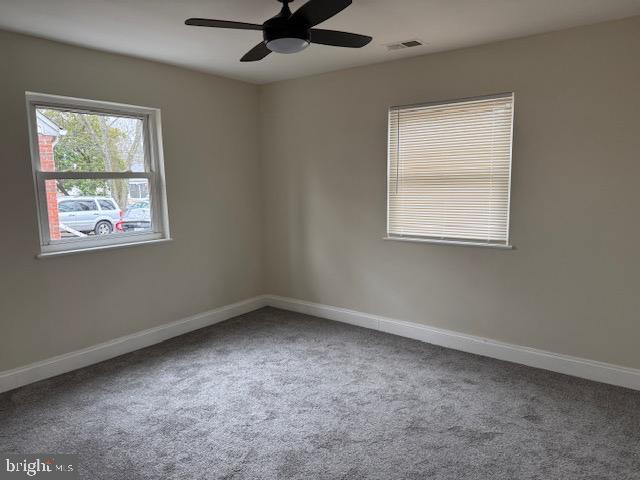 spare room featuring ceiling fan, visible vents, baseboards, and carpet flooring