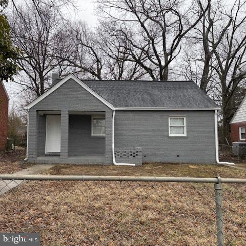 view of front of house featuring brick siding, crawl space, a shingled roof, and fence