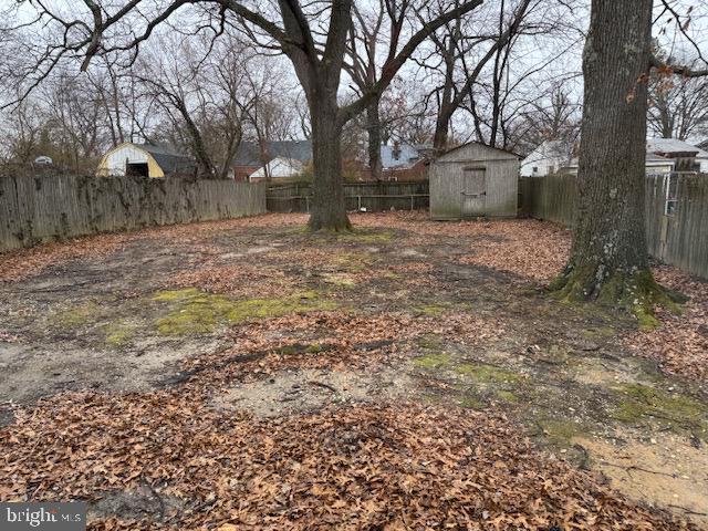 view of yard with a fenced backyard, a storage unit, and an outbuilding