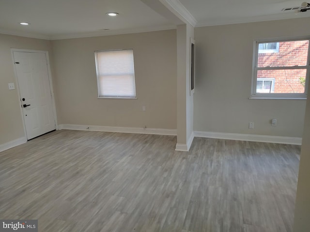 unfurnished room with visible vents, ornamental molding, light wood-style flooring, and baseboards