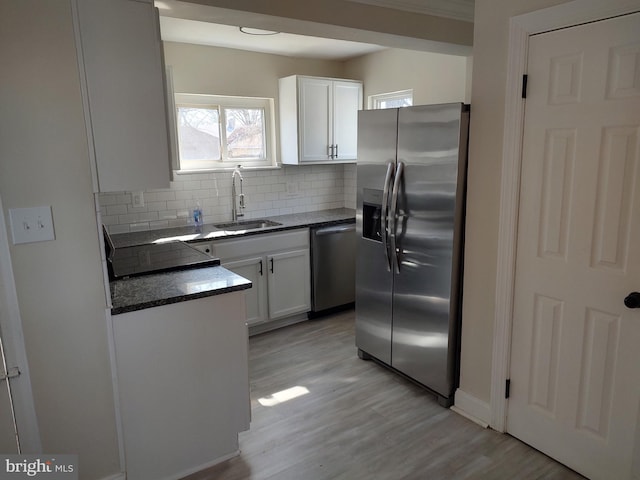 kitchen with tasteful backsplash, appliances with stainless steel finishes, light wood-type flooring, white cabinetry, and a sink