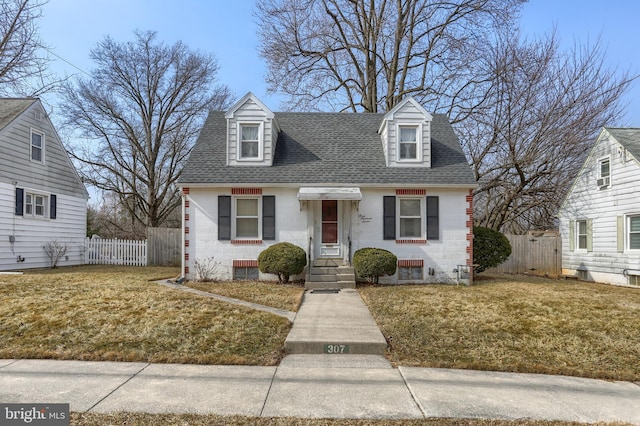 new england style home with a front yard, roof with shingles, and fence