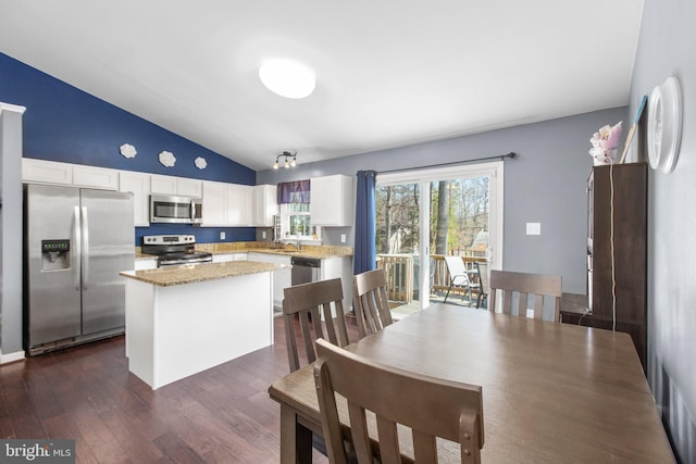 kitchen featuring a center island, lofted ceiling, appliances with stainless steel finishes, dark wood-style floors, and white cabinets