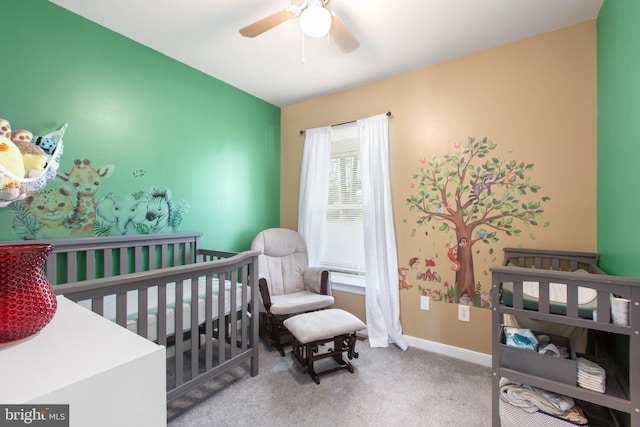 carpeted bedroom featuring baseboards, a nursery area, and a ceiling fan