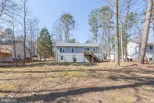 rear view of house with a wooden deck, stairs, a yard, and fence