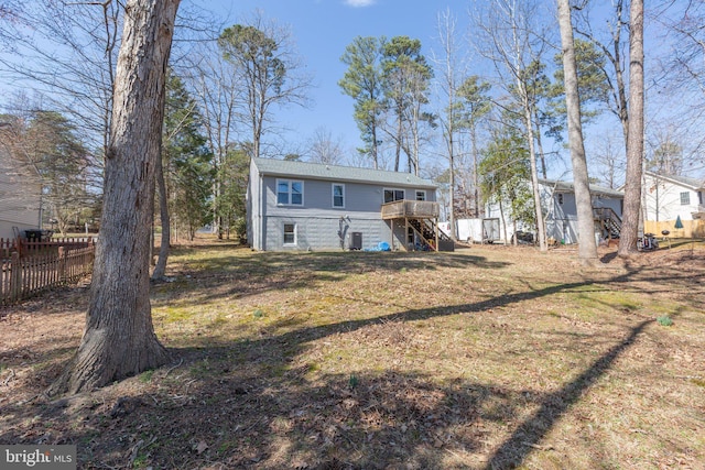 rear view of house with a lawn, a wooden deck, stairs, and fence