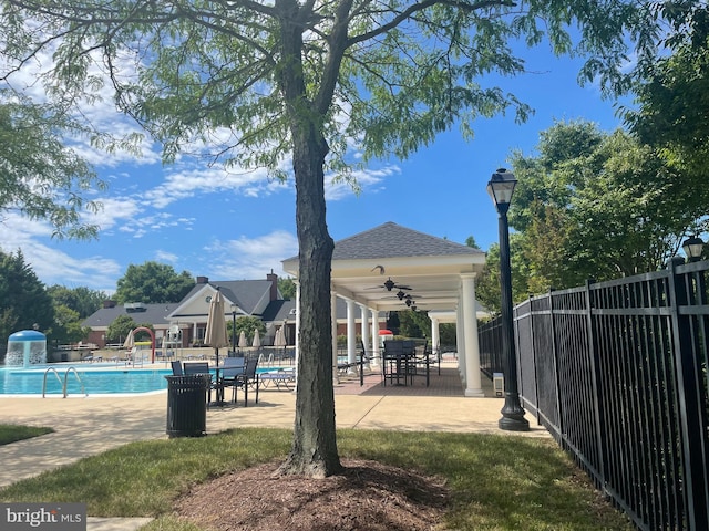 community pool with a patio area, fence, and a ceiling fan