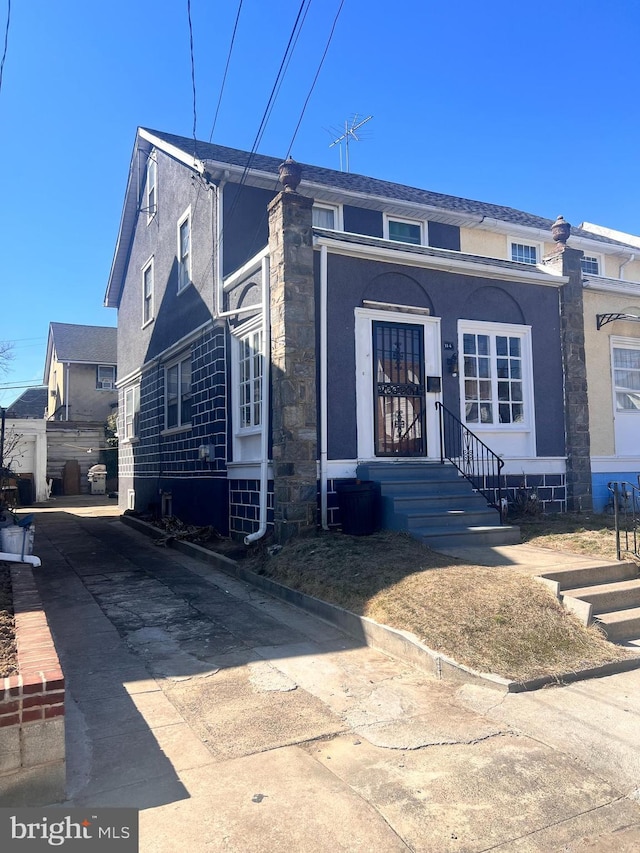 view of front of home featuring stone siding, stucco siding, and entry steps