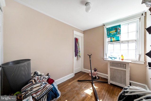 workout room featuring crown molding, radiator heating unit, wood finished floors, and baseboards