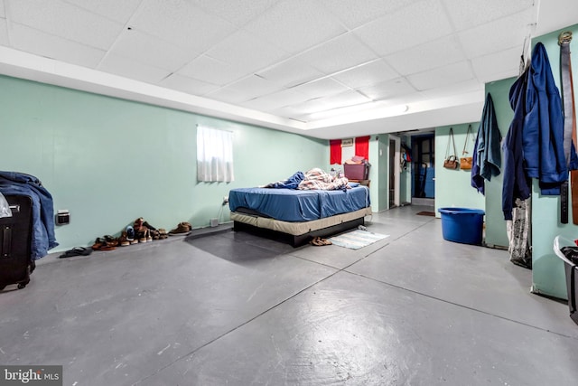 bedroom with finished concrete flooring and a paneled ceiling