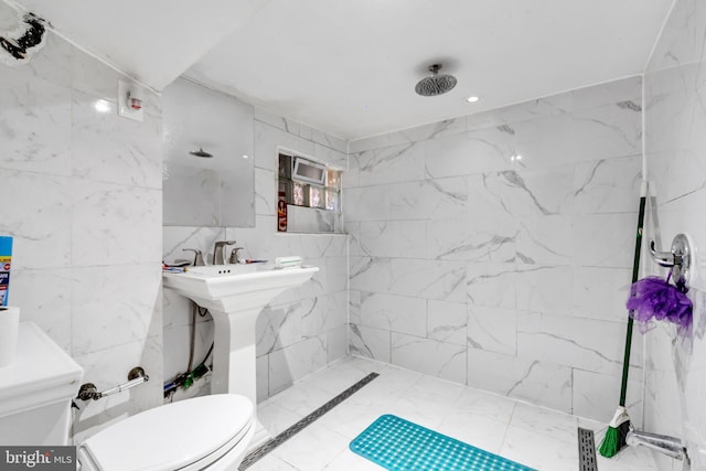 full bath featuring toilet, tiled shower, and tile walls