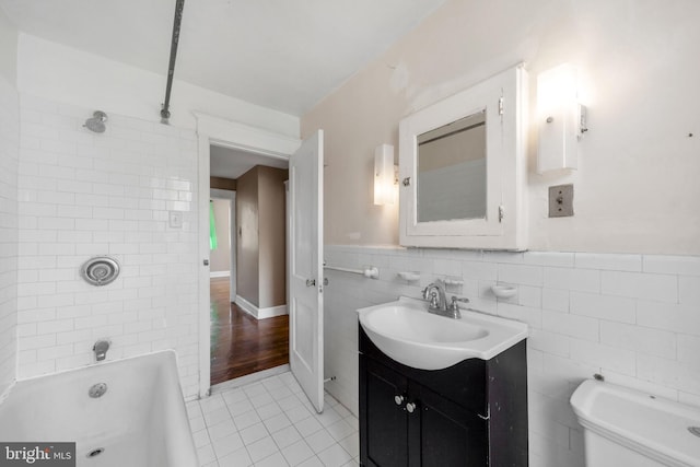 bathroom with tile walls, tile patterned flooring, vanity, toilet, and washtub / shower combination