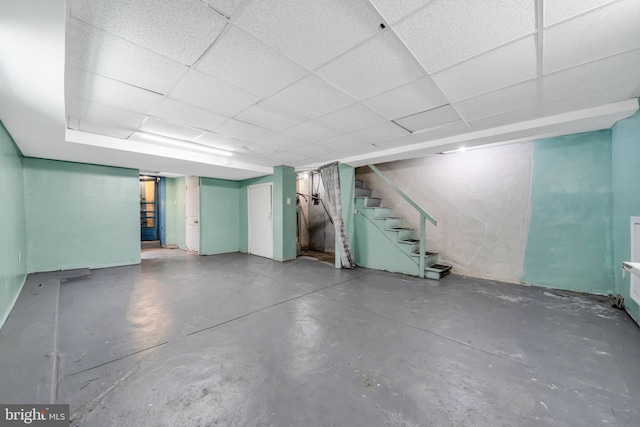finished below grade area featuring stairway and a paneled ceiling
