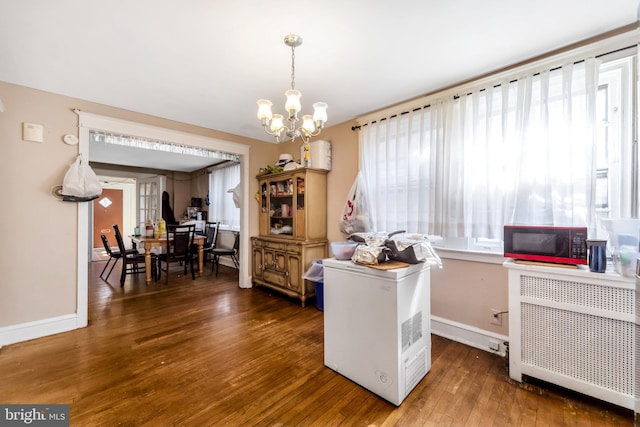 interior space featuring radiator, baseboards, black microwave, an inviting chandelier, and hardwood / wood-style flooring