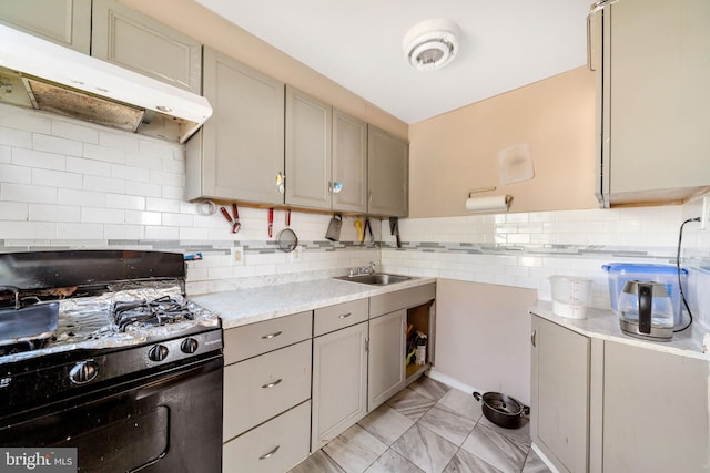 kitchen featuring gray cabinets, a sink, light countertops, black gas range, and under cabinet range hood