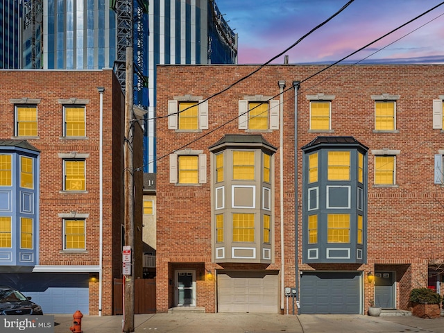 townhome / multi-family property featuring a garage, brick siding, and driveway