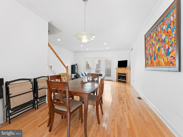 dining space featuring light wood finished floors, a fireplace, and crown molding