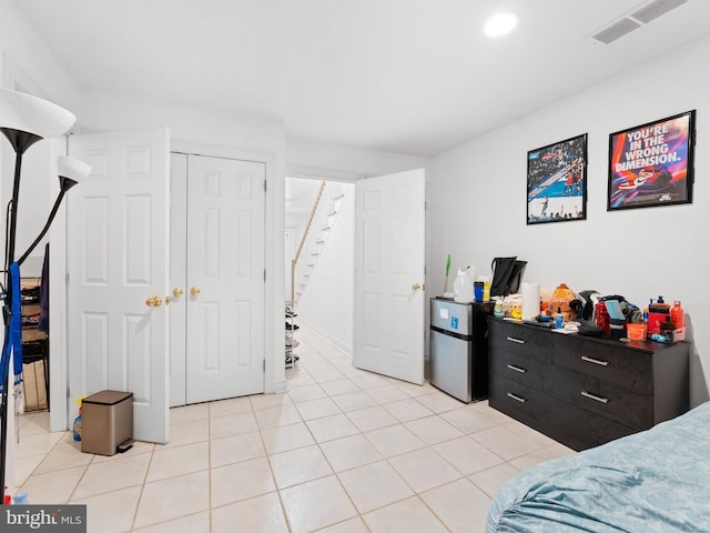 bedroom with light tile patterned floors, visible vents, recessed lighting, and freestanding refrigerator