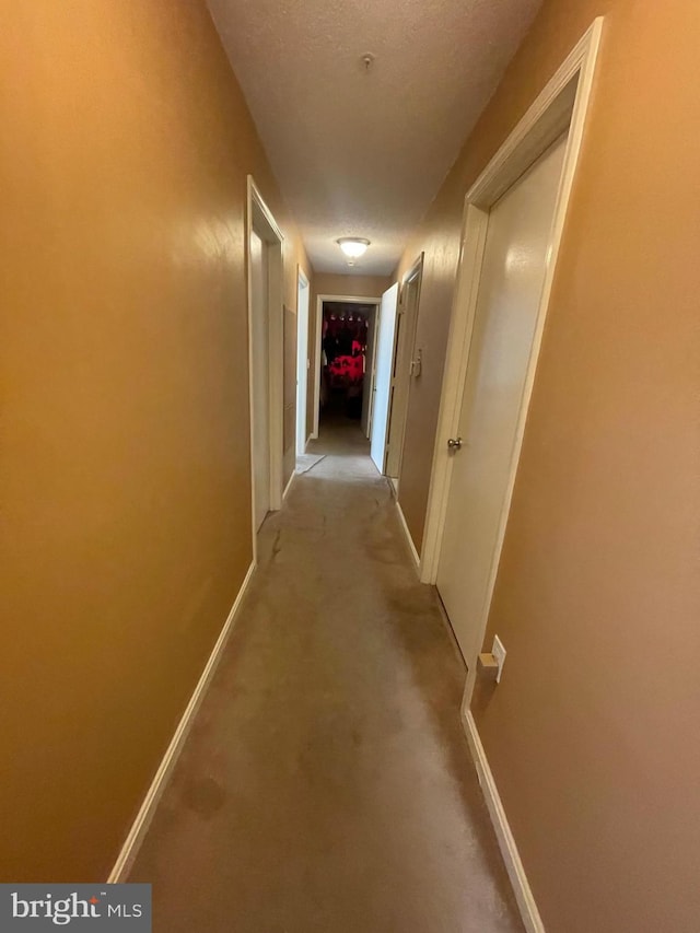 hallway with a textured ceiling and baseboards