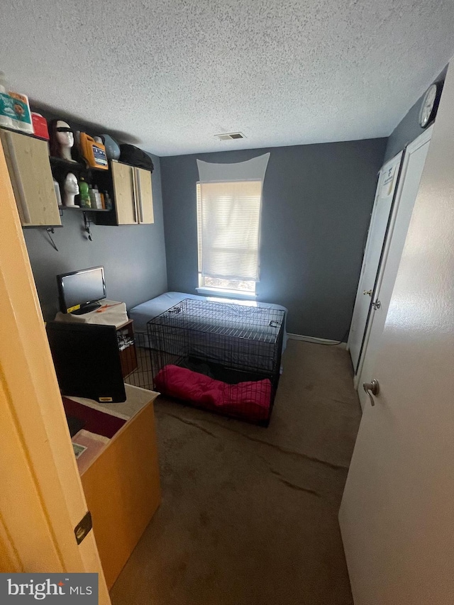 bedroom featuring carpet, visible vents, and a textured ceiling