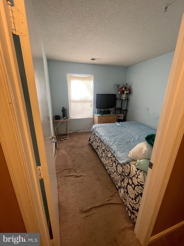 bedroom featuring visible vents, a textured ceiling, and carpet floors