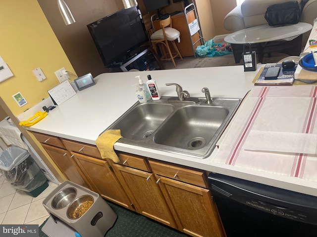 kitchen with a sink, dishwasher, brown cabinetry, and light countertops