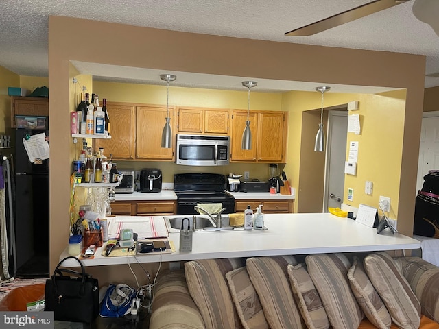 kitchen featuring a breakfast bar, light countertops, a peninsula, a textured ceiling, and black appliances