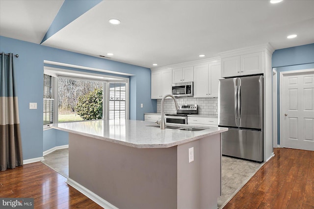 kitchen with a sink, stainless steel appliances, tasteful backsplash, and white cabinetry