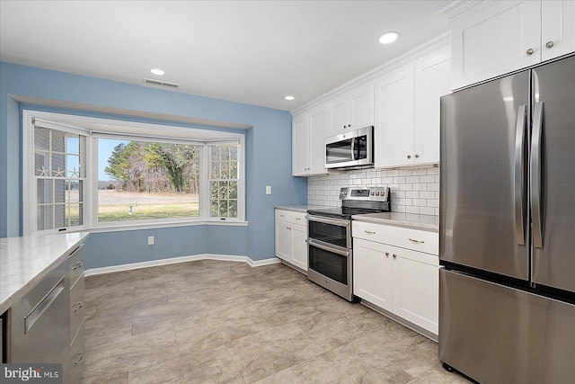 kitchen with baseboards, visible vents, appliances with stainless steel finishes, white cabinetry, and backsplash