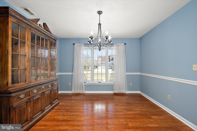 unfurnished dining area with an inviting chandelier, dark wood-style floors, visible vents, and baseboards