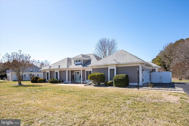 view of front facade with a garage, a shingled roof, a front lawn, and a gate