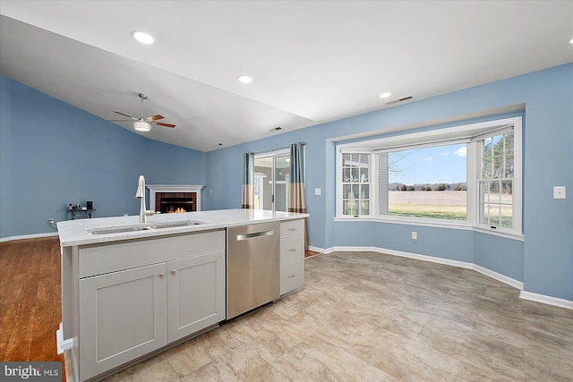 kitchen featuring a sink, stainless steel dishwasher, open floor plan, baseboards, and ceiling fan