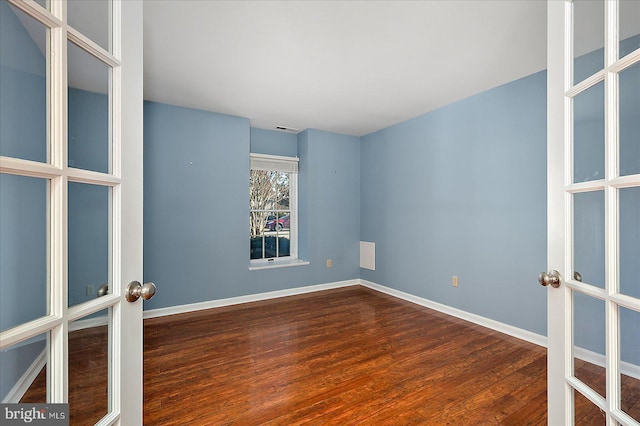 unfurnished room with wood finished floors, french doors, and baseboards