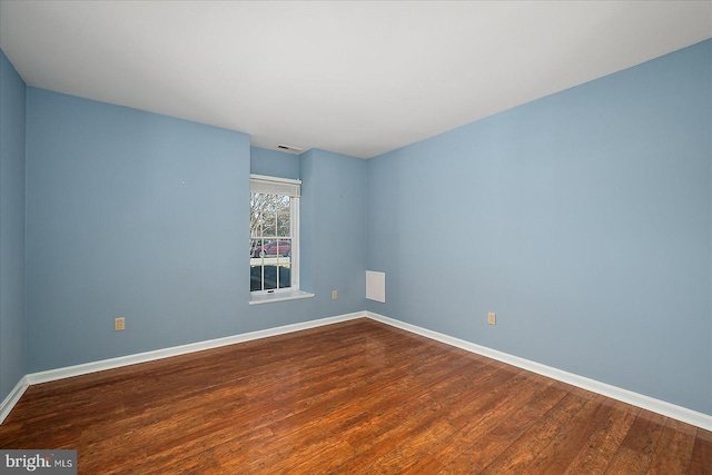 spare room featuring visible vents, baseboards, and wood finished floors