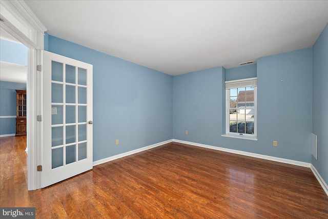 unfurnished room with wood finished floors, visible vents, and baseboards