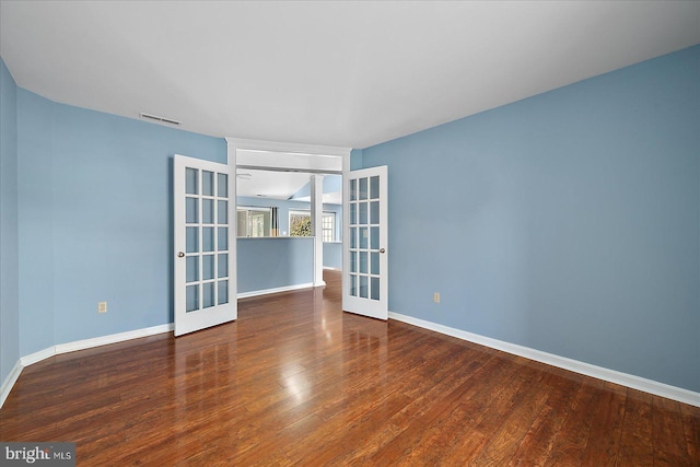 unfurnished room with wood finished floors, french doors, visible vents, and baseboards