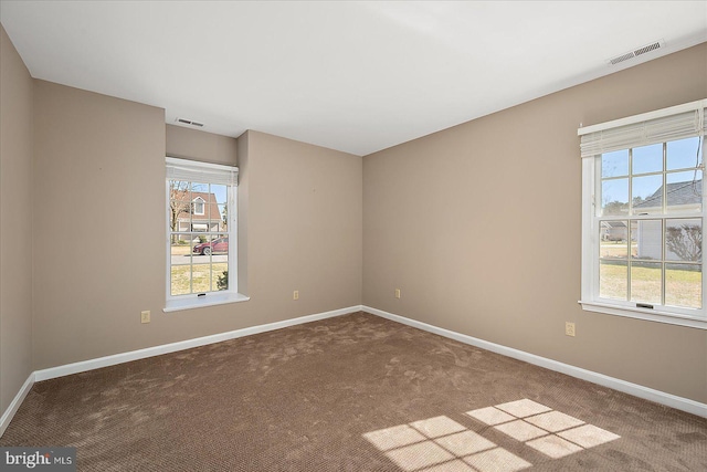 empty room with visible vents, plenty of natural light, and baseboards