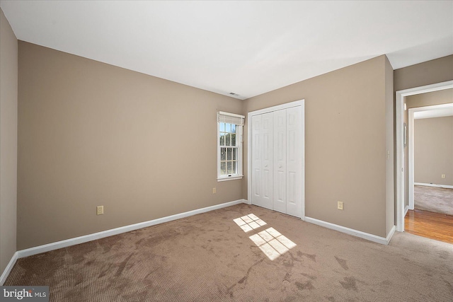 unfurnished bedroom with a closet, baseboards, and carpet flooring