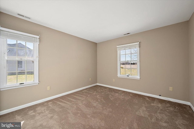 carpeted spare room featuring visible vents and baseboards